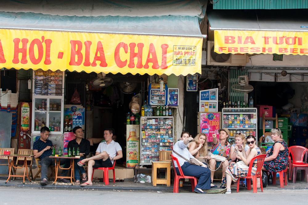 des gens assis dans un resto de bière sur le trottoir à Hanoi et buvant de la bière avec des amis