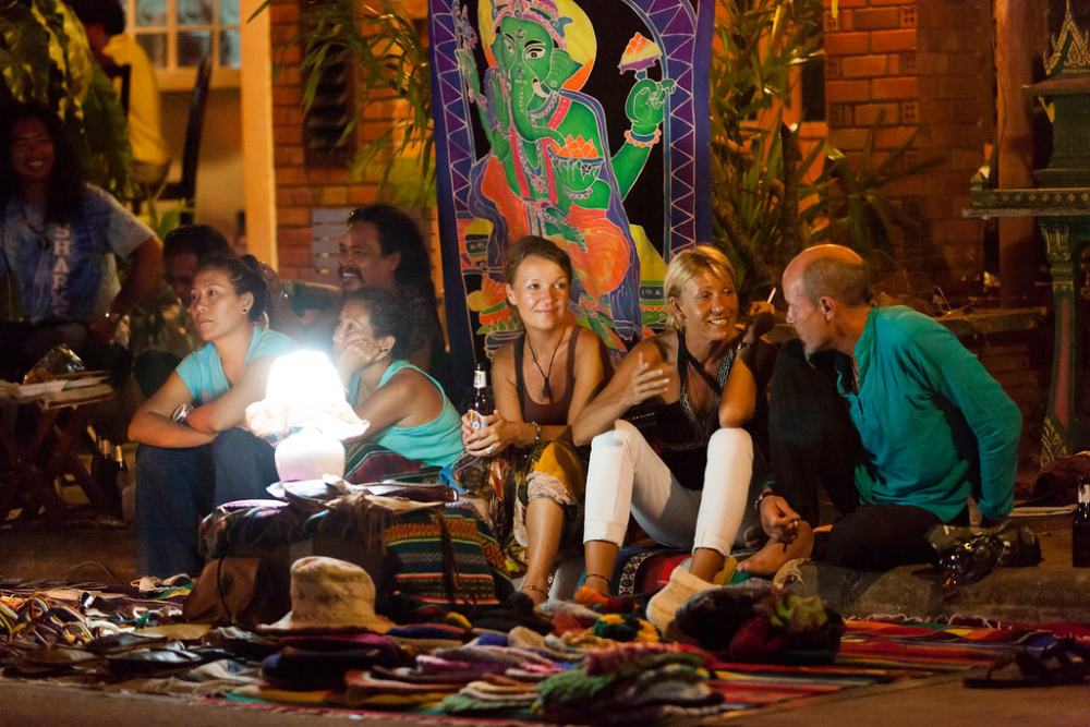 voyageurs parlent aux habitants locaux dans un marché norturne en Thaïlande