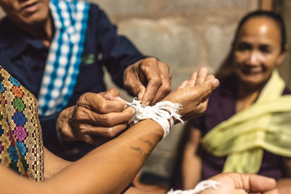 nouage de fils de coton blanc autour du poignet, cérémonie du baci au Laos, voyage au Laos, culture laotienne