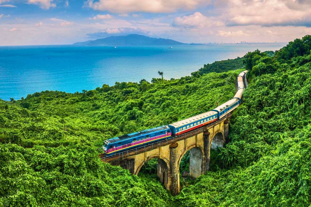 train Da Nang Hue traversant un pont au milieu de nature verdoyante avec vue sur la mer