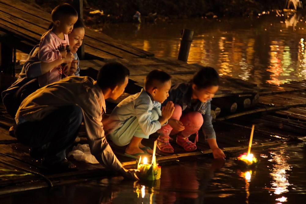 famille locale déposant des krathong sur la rivières lors du festival Loy Krathong