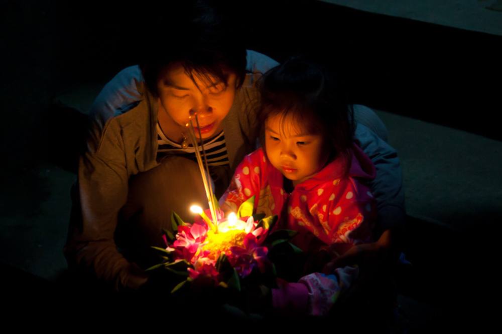 mère et fille thaïlandaise priant avant de libérer un krathong 