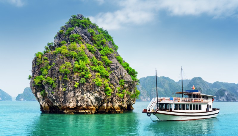 une croisière s'approchant d'un îlot dans la baie d'Halong