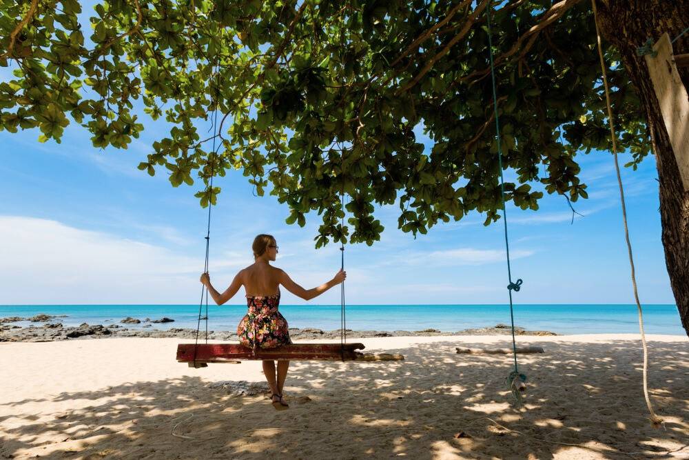 une voyageuse solo sur une balançoire sur la plage à l'île de Koh Lanta