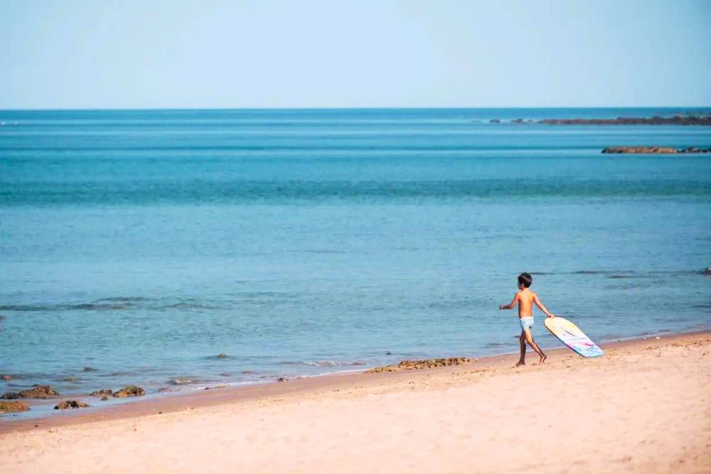 un enfant tenant une planche de surf sur l'île de Koh Lanta