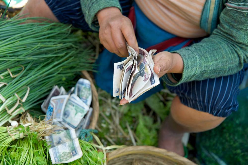 une vendeuse au marché au Laos compte des billets de kip