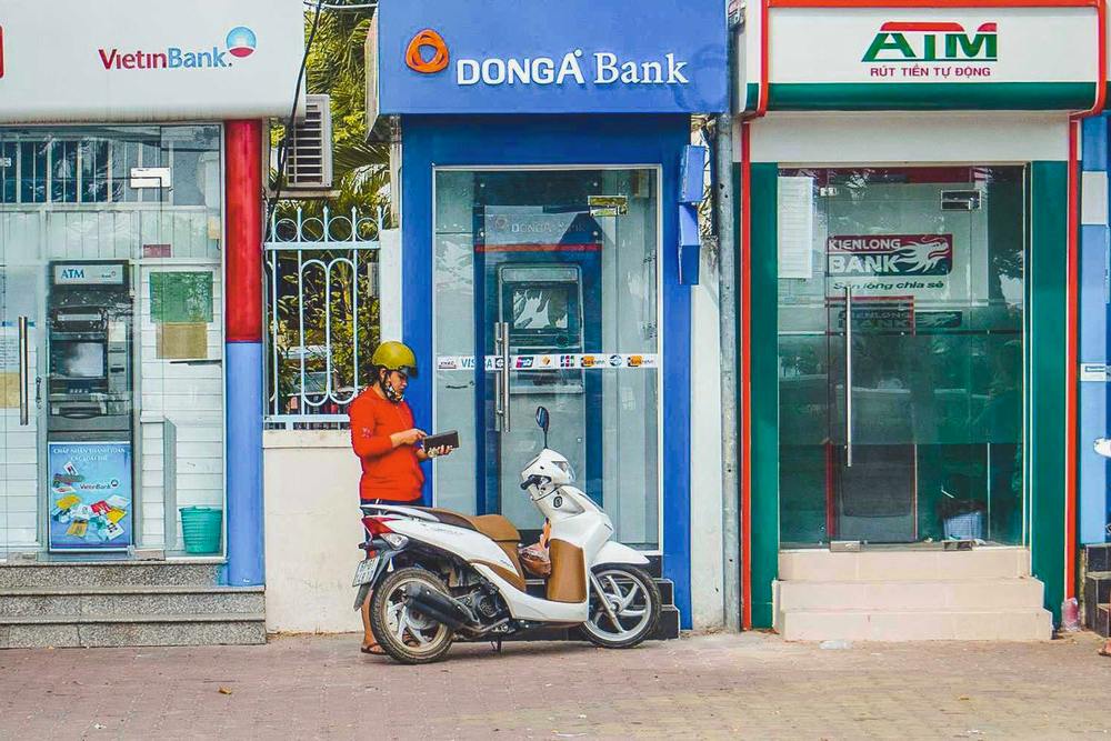 une femme devant une rangée de distributeurs automatiques d'argent au Vietnam