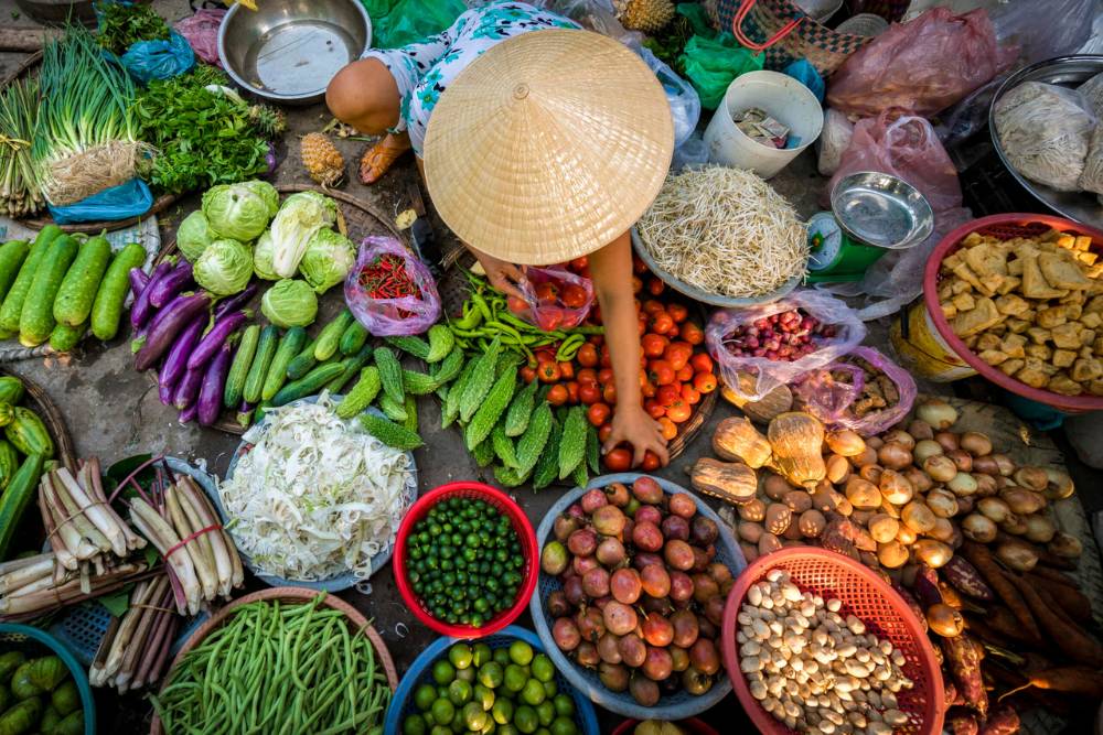 femmes vietnamiennes au marché vendant une large variété de légumes et fruits frais colorés