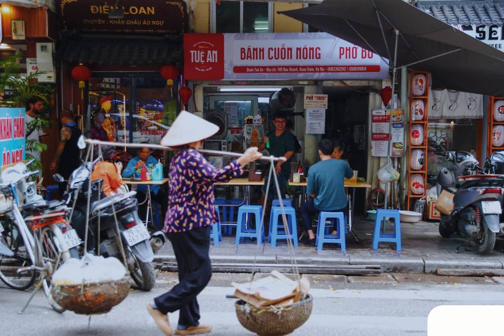 une vendeuse ambulante passe devant le restaurant du pho treo à Hanoi