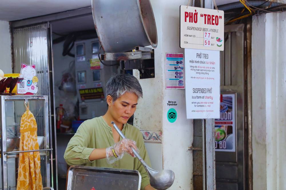 Madame Lê la patronne prépare des bols de pho treo pour les démunis