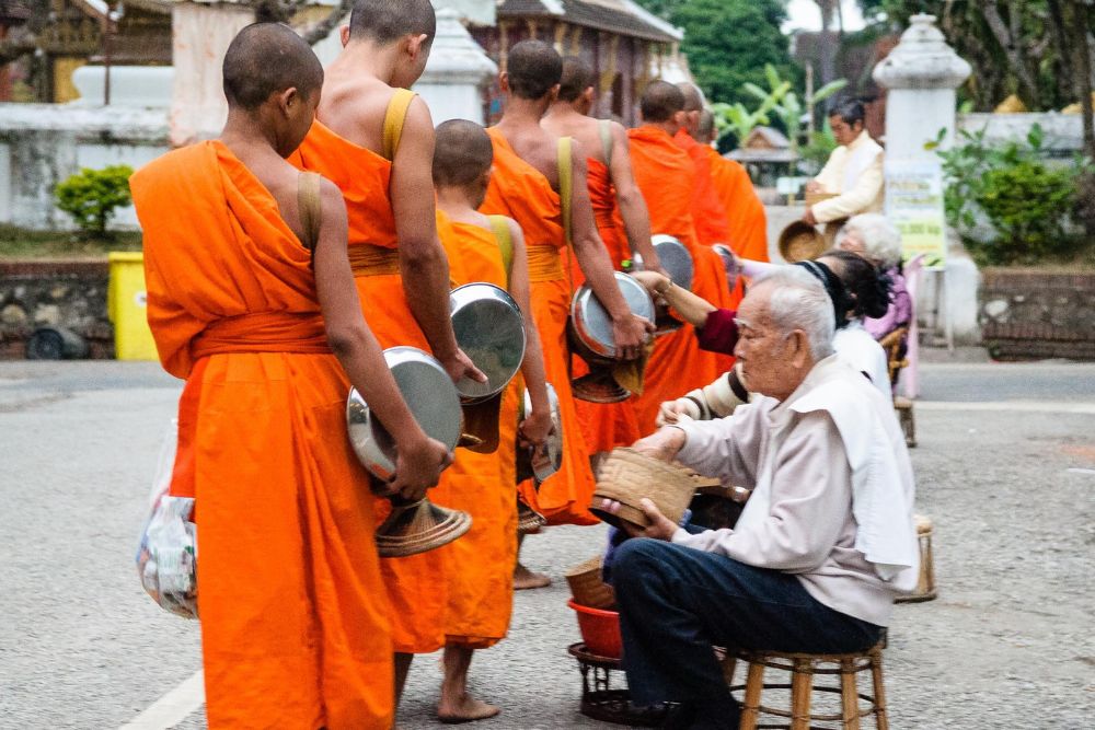 tak bat, cérémonie de l'aumône, homme faisant l'aumône aux moines, luang prabang, laos