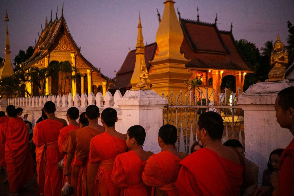 tak bat, cérémonie de l'aumône, moines marchant en ligne devant un temple tôt le matin, luang prabang, laos