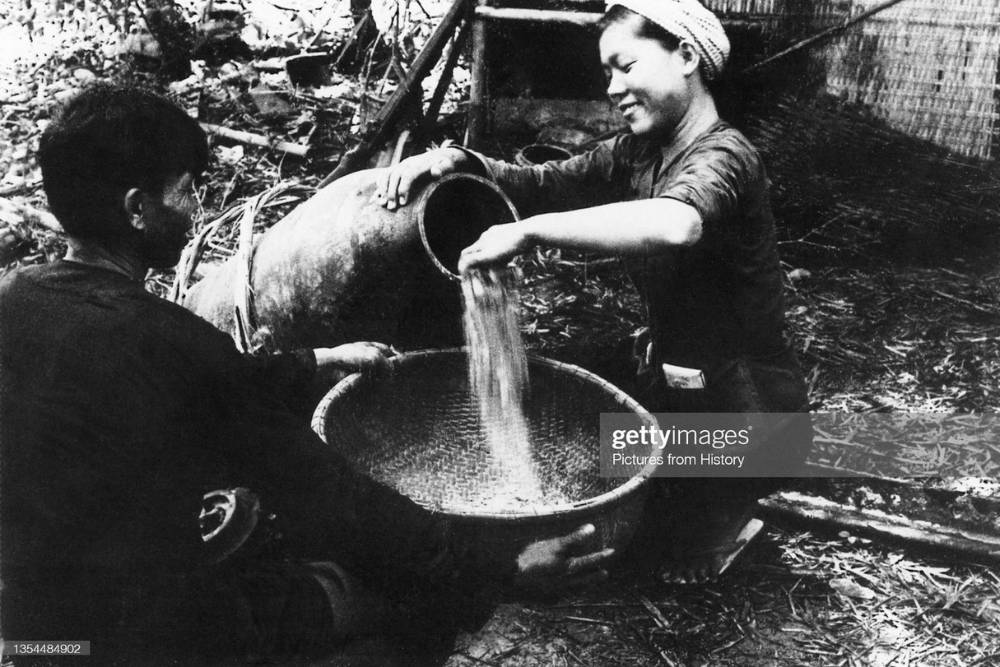 en noir et blanc, les habitants de Cu Chi démontent les bombes pour récupérer la poudre à canon