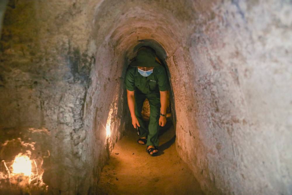 un guide se déplace dans un tout petit tunnel de Cu Chi