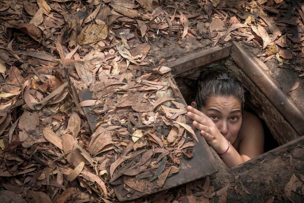 une voyageuse se cache derrière une petite trappe aux tunnels de Cu Chi